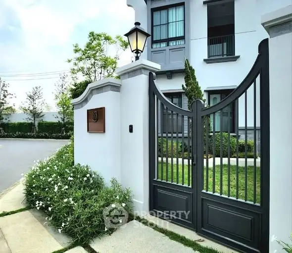 Elegant entrance gate of modern home with lush greenery and stylish design.