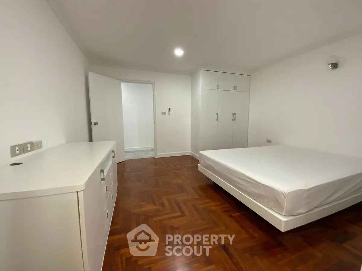 Spacious bedroom with wooden flooring and built-in wardrobe