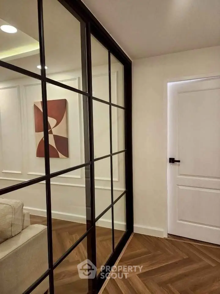 Modern interior with glass partition and stylish artwork, featuring elegant herringbone flooring.