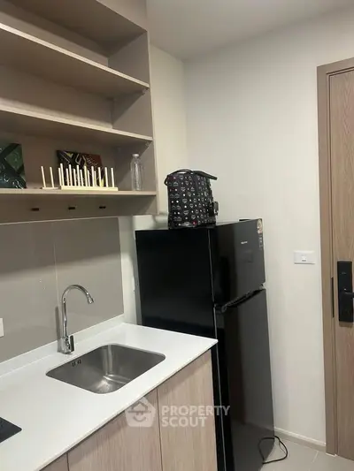 Modern kitchen with sleek cabinetry and compact fridge in a stylish apartment.