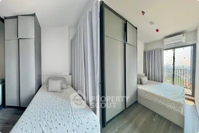 Modern bedroom with single bed and city view balcony, ideal for urban living.