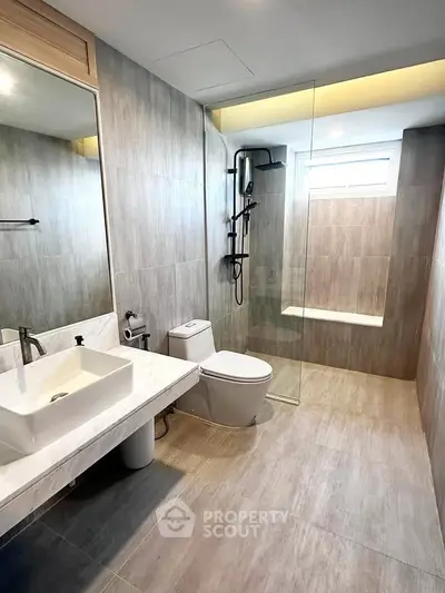 Modern bathroom with sleek design, featuring a glass shower and elegant fixtures.