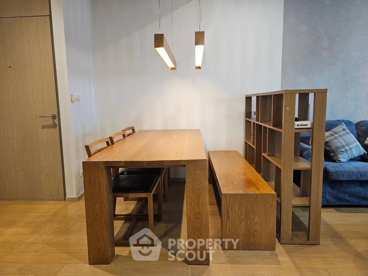 Modern dining area with wooden table, chairs, and stylish lighting in cozy apartment.