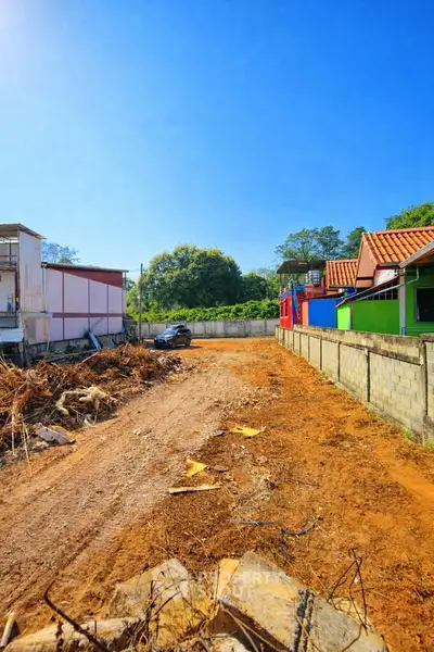 Vacant land plot with clear blue sky, ideal for new construction in a vibrant neighborhood.