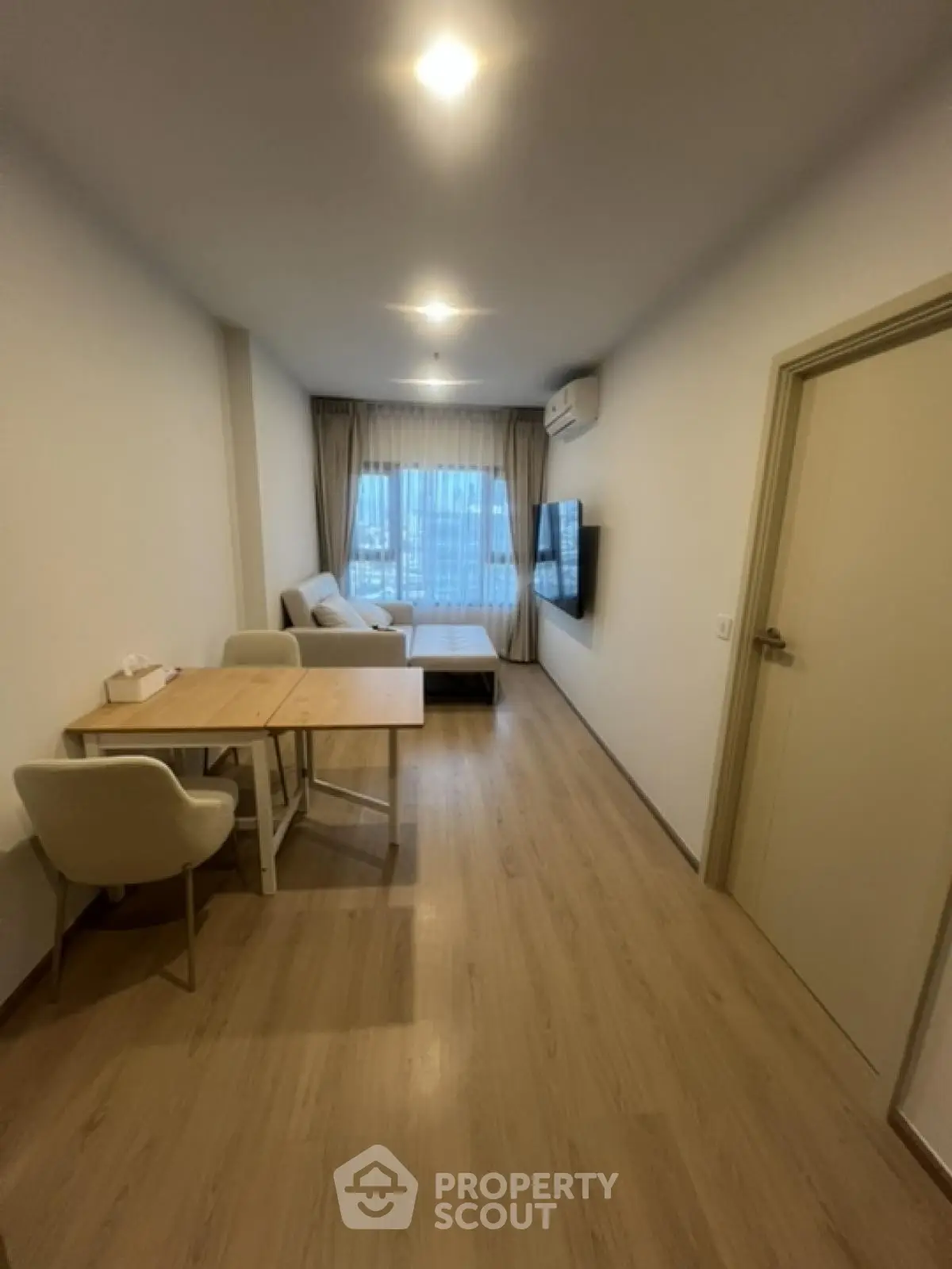 Modern living room with wooden flooring and cozy furniture in a high-rise apartment.