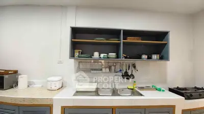 Modern kitchen with open shelving and gas stove, featuring sleek countertops and organized dishware.