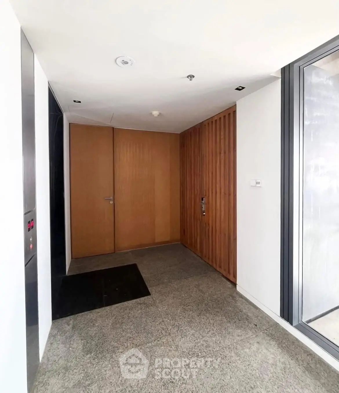 Modern building entrance with sleek elevator and wooden paneling