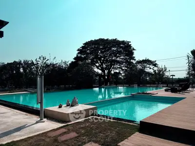 Luxurious outdoor pool area with wooden deck and lush greenery, perfect for relaxation and leisure.