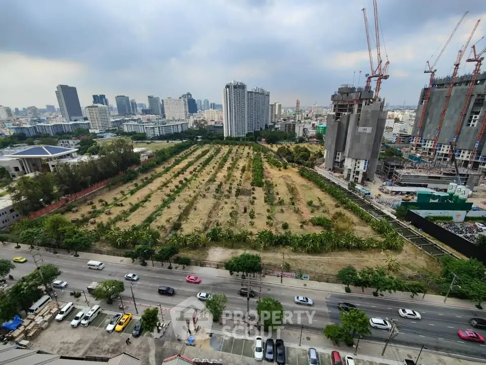 Aerial view of urban development site with city skyline and construction cranes.