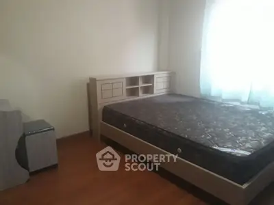 Cozy bedroom with wooden flooring and natural light, featuring a comfortable bed and modern furniture.
