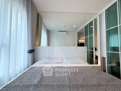 Modern bedroom with mirrored wall and large window in stylish apartment