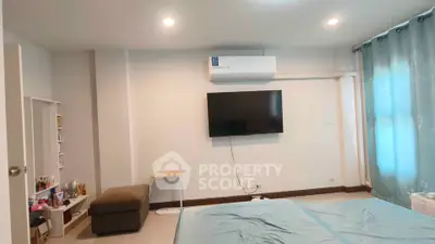 Modern bedroom with wall-mounted TV and air conditioning, featuring elegant curtains and cozy decor.