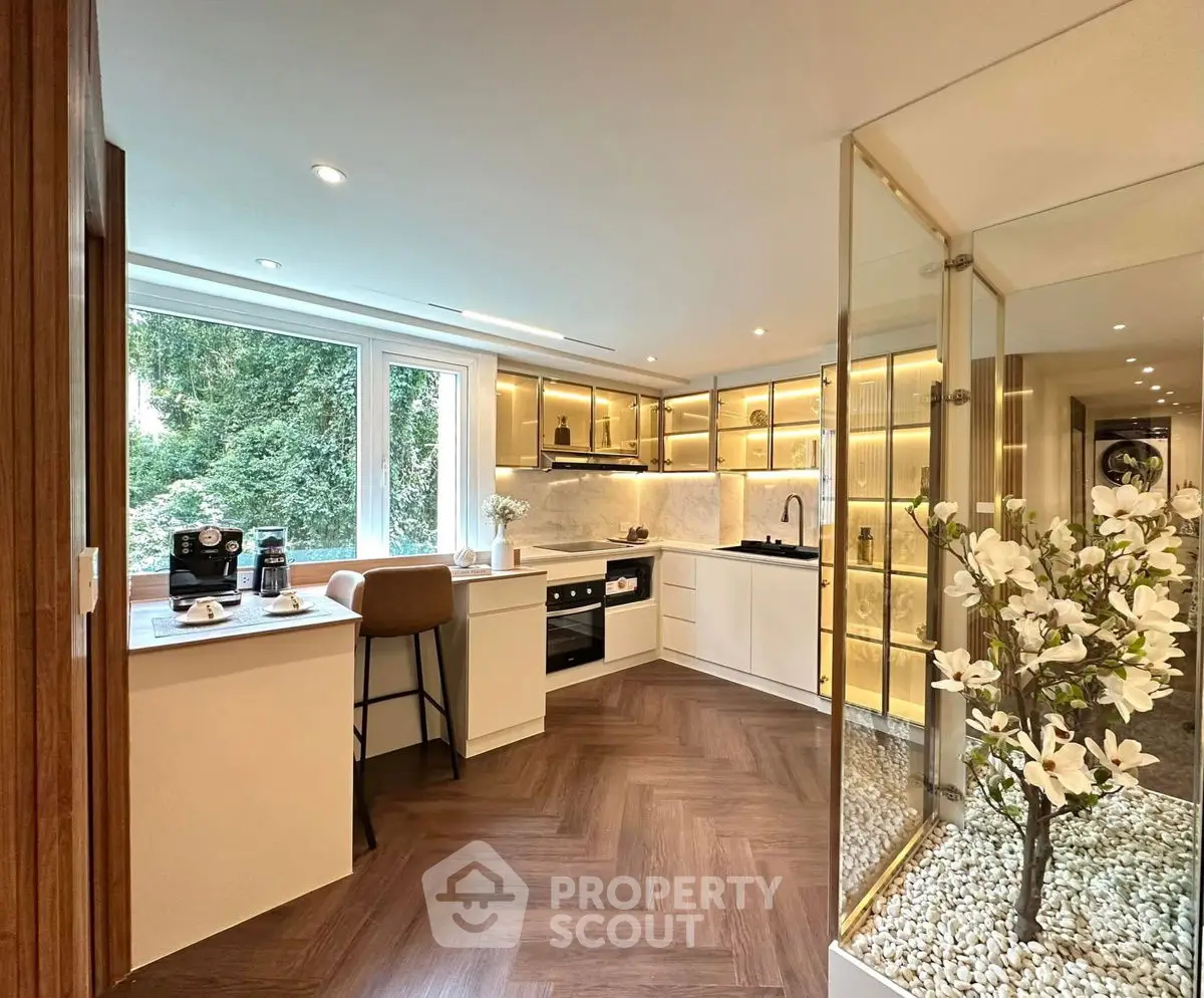 Luxurious kitchen with open layout, modern appliances, and elegant decor overlooking lush greenery.