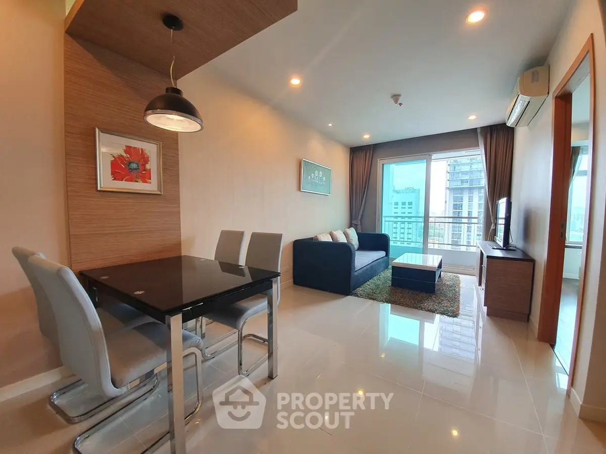 Modern living room with dining area and city view, featuring sleek furniture and contemporary decor.