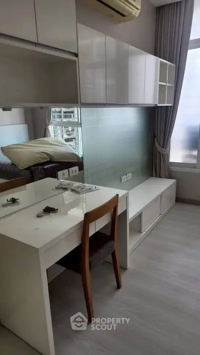 Modern compact living room with sleek furniture and large window for natural light.