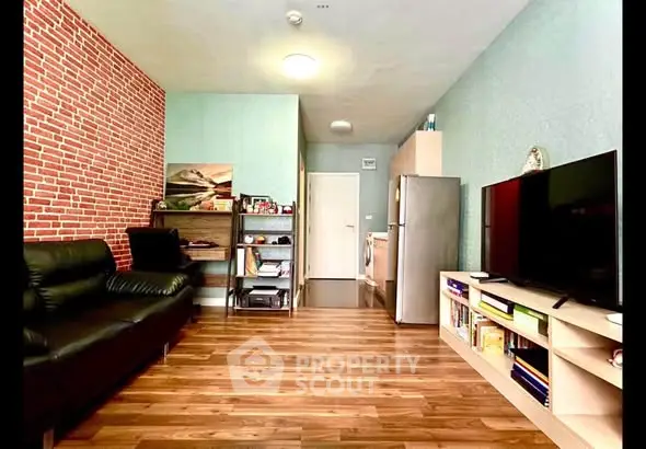 Modern living room with brick accent wall, sleek black sofa, and large TV unit in stylish apartment.