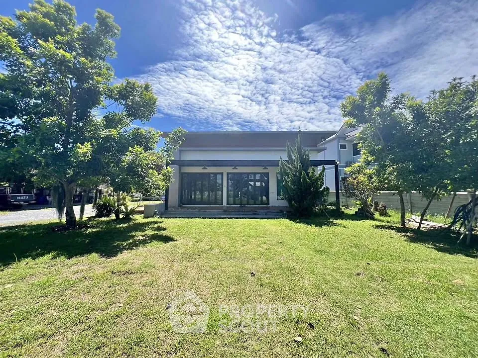 Modern house with large windows and lush green lawn under a clear blue sky.