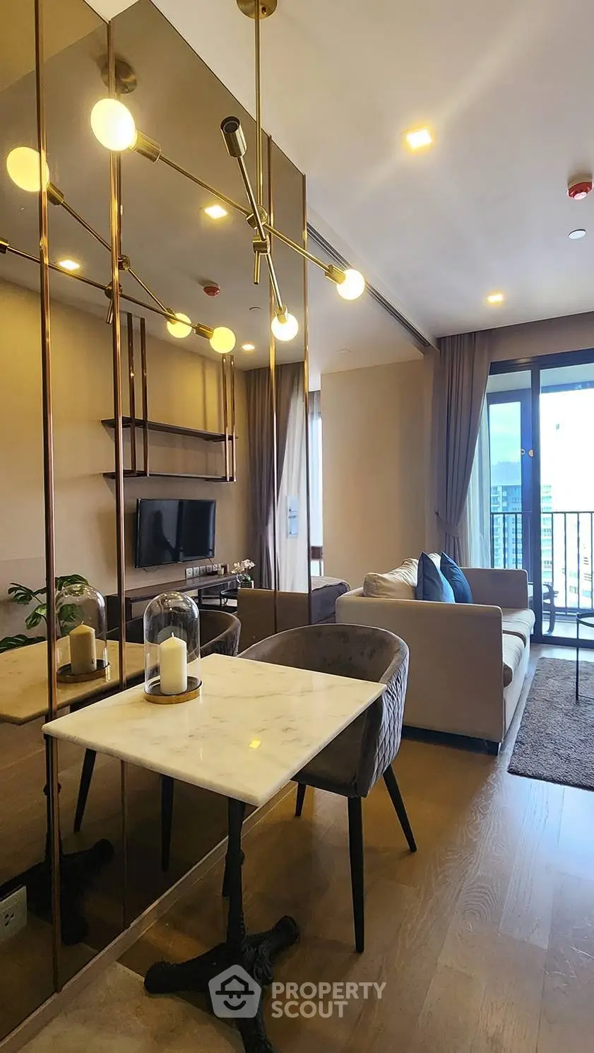 Modern living room with elegant decor and large windows leading to a balcony, featuring stylish lighting and cozy seating.