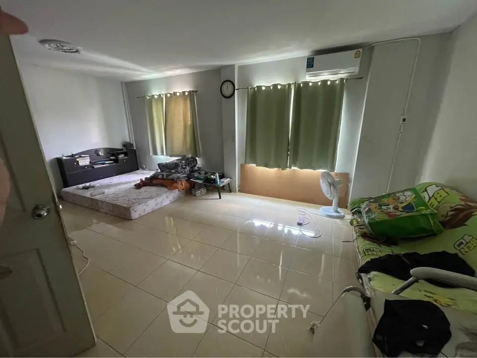 Spacious bedroom with tiled floor, air conditioning, and natural light from large windows.