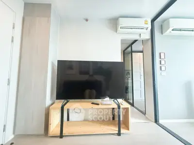 Modern living room with sleek TV setup and air conditioning in a stylish apartment.