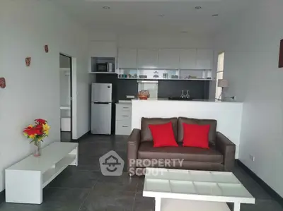 Modern living room with sleek kitchen and stylish decor, featuring a cozy sofa and vibrant accents.