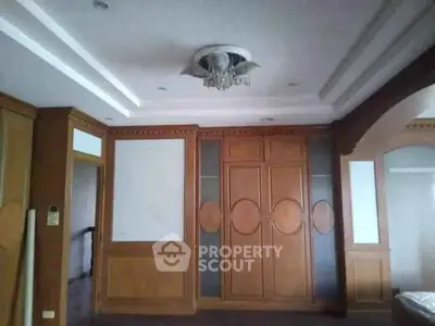 Spacious living room with elegant wooden paneling and decorative ceiling light fixture.