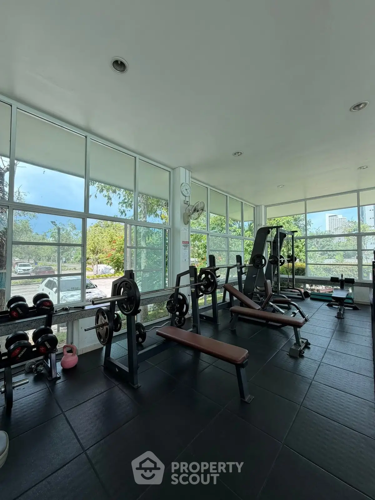 Spacious gym with modern equipment and large windows offering a scenic view, perfect for fitness enthusiasts.