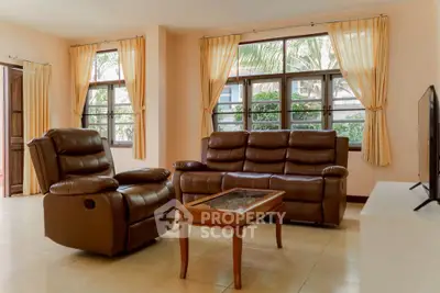 Spacious living room with leather sofas and large windows offering natural light.