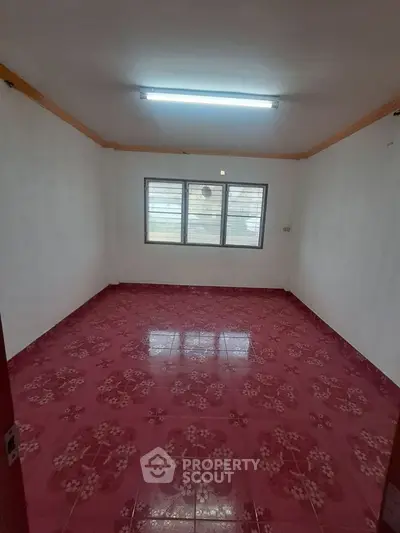 Spacious room with vibrant red floral tiles and large window for natural light.