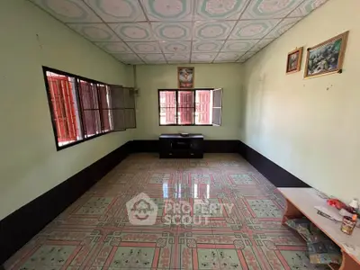 Spacious living room with patterned tile flooring and open windows for natural light.