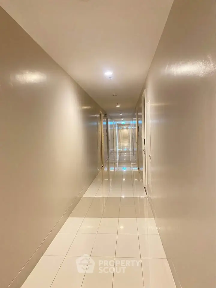 Spacious and well-lit hallway with modern tile flooring in a residential building.
