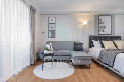 Modern living room with stylish decor and cozy seating area next to a comfortable bed.