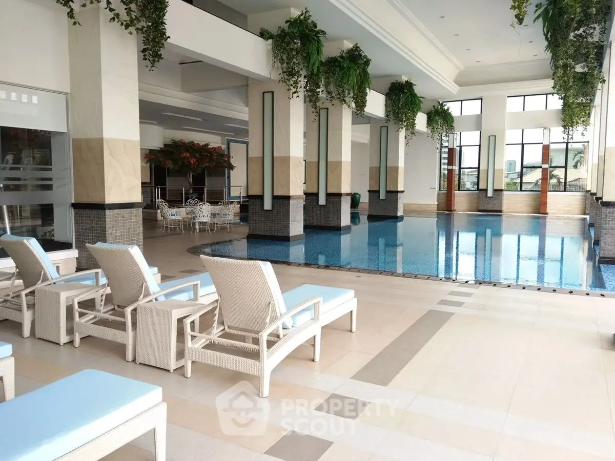 Luxurious indoor pool area with elegant lounge chairs and lush greenery, perfect for relaxation and leisure.