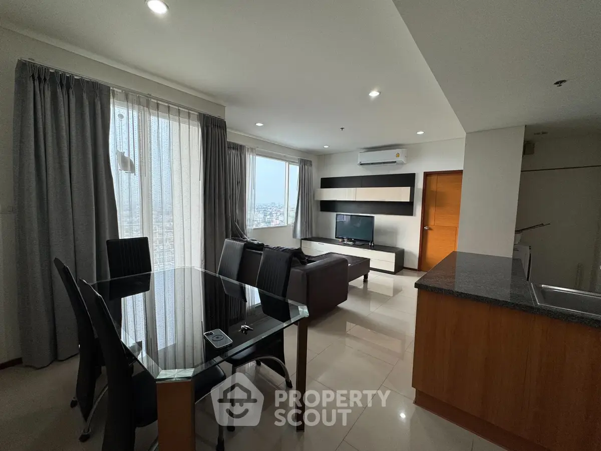 Modern living room with dining area and city view, featuring sleek furniture and ample natural light.