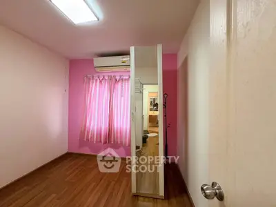 Charming bedroom with pink accents and mirrored wardrobe, featuring hardwood floors and air conditioning.