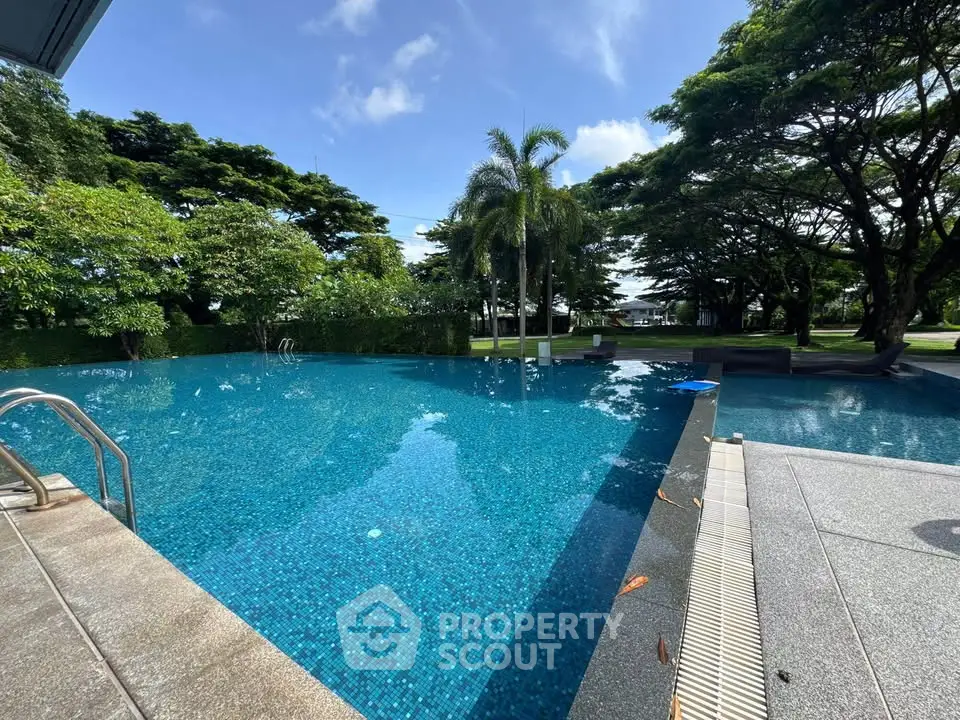 Luxurious outdoor pool surrounded by lush greenery and palm trees, perfect for relaxation and leisure.