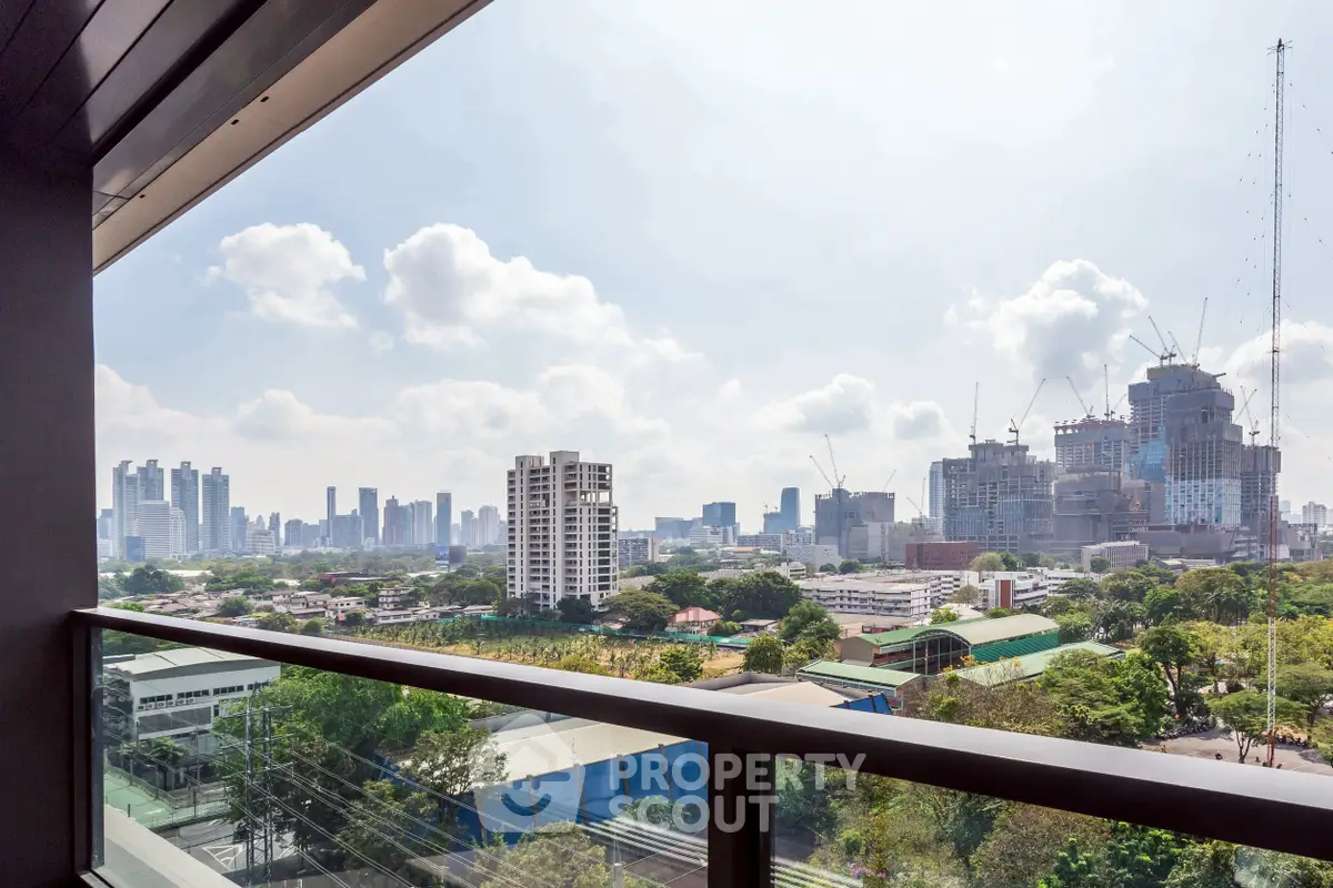 Stunning cityscape view from a modern balcony, showcasing urban skyline and lush greenery.