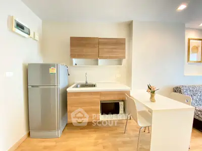 Modern kitchen with sleek cabinets, stainless steel fridge, and compact dining area.