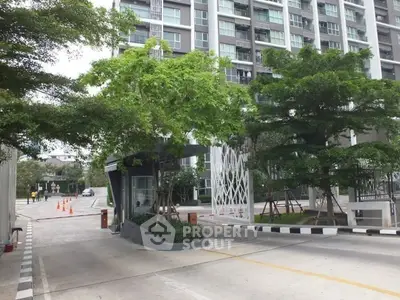 Modern residential building entrance with lush greenery and secure access.