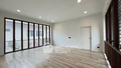 Spacious empty room with large windows and wooden flooring, perfect for customization.