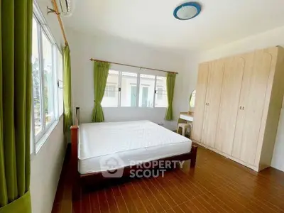 Spacious bedroom with large windows and wooden flooring