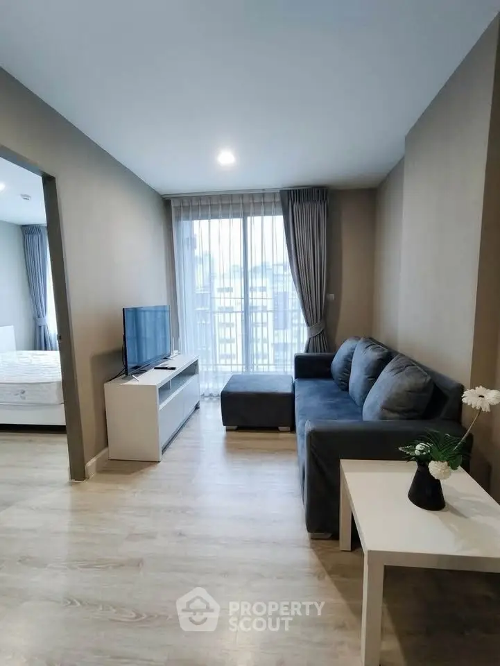 Modern living room with sleek furniture and large window offering natural light.