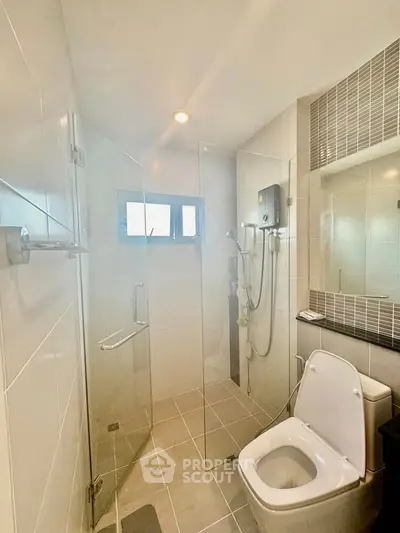 Modern bathroom with glass shower and sleek fixtures in contemporary home.