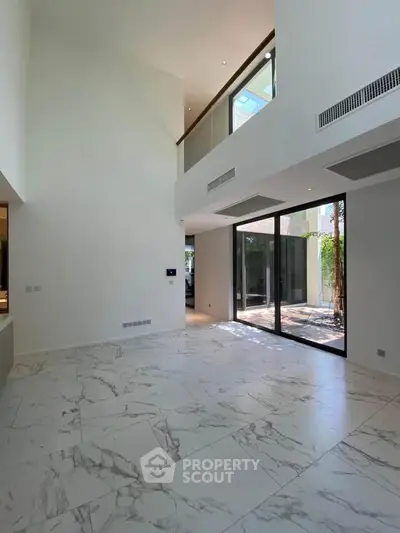 Spacious modern living room with high ceilings and large windows offering natural light.