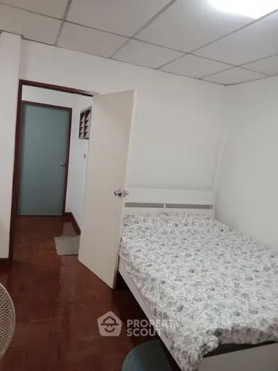 Cozy bedroom with wooden flooring and a comfortable bed in a minimalist design.