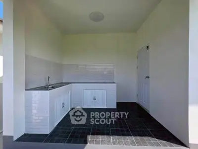 Modern minimalist outdoor kitchen with sleek white cabinetry and tiled backsplash.