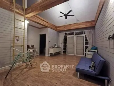 Spacious living room with high ceiling and modern decor, featuring a blue sofa and wooden accents.