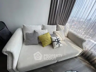 Stylish living room with cozy sofa and city view through large window.