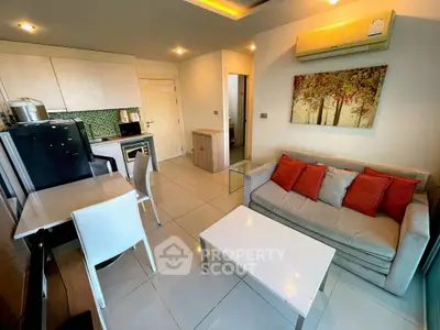 Modern living room with open kitchen, featuring stylish decor and ample natural light.