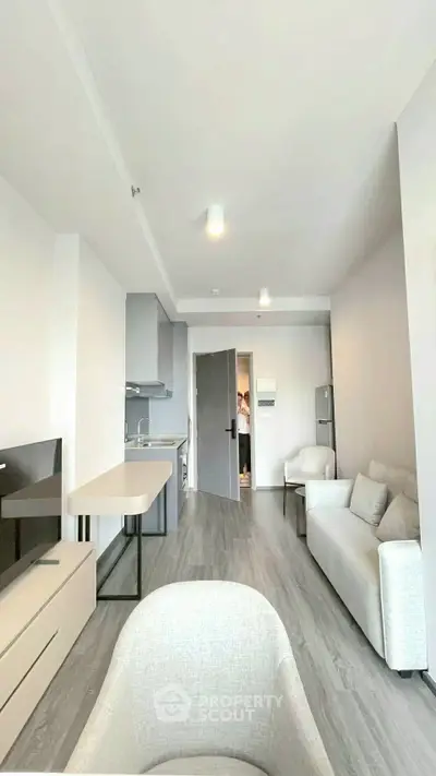 Modern open-plan living room with sleek kitchen and stylish furniture in a bright apartment.